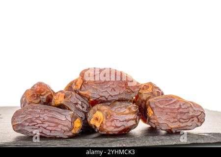 Several sweet dried pitted dates with slate stone, macro, isolated on white background. Stock Photo