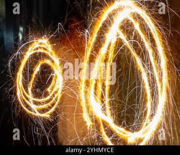 Golden light trails dance in the night, creating mesmerizing circles of sparkling energy. Perfect for festive designs and celebratory backgrounds. Stock Photo