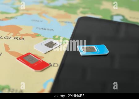 SIM cards and smartphone on world map, closeup Stock Photo