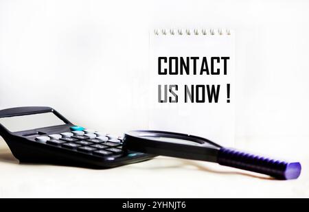 Text CONTACT US NOW on a notepad .Business concept Stock Photo