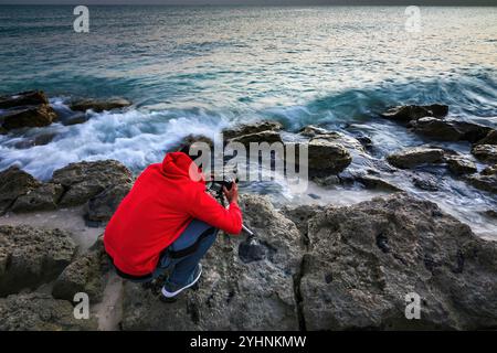 A photographer standing in front of the sea to take photo. RasTanura Beach, Saudi Arabia. 07-June-2023 Stock Photo