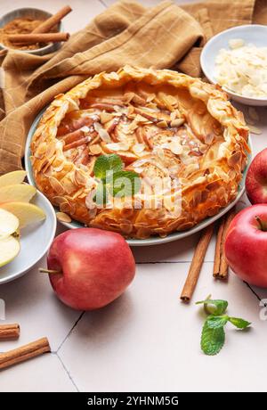 A freshly baked apple galette is displayed with slices of crisp apples, almond flakes, and a sprinkle of cinnamon, creating a warm, inviting atmospher Stock Photo