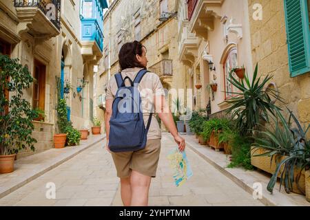 Woman traveler exploring touristic town Birgu on Malta island with a map Stock Photo