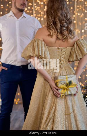 Woman hides Christmas gift for her husband behind her back Stock Photo