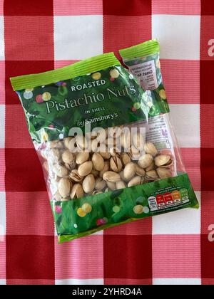 Opened bag of Roasted Pistachio nuts on a red checked tablecloth Stock Photo