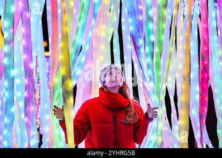 London, UK. 12th Nov, 2024. Models pose in the 'Christmas Presents' installation by Culture Creative. Shaped as presents with bows on top, visitors walk through candy coloured ribbons. The annual Christmas at Kew illuminations and light trail at Kew Gardens returns for its 12th year with thousands of dazzling lights, sounds, and immersive experiences along the 3km trail. It will be open from 13th Nov until 5th Jan. Credit: Imageplotter/Alamy Live News Stock Photo