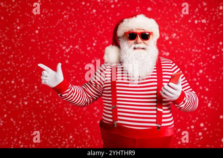 Portrait of his he nice handsome cheerful bearded fat overweight Santa using device app 5g showing copy space shopping gift present surprise isolated Stock Photo