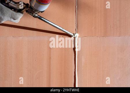 Using construction foam to seal seams with a tube. Laying polyurethane foam on the floor. Stock Photo