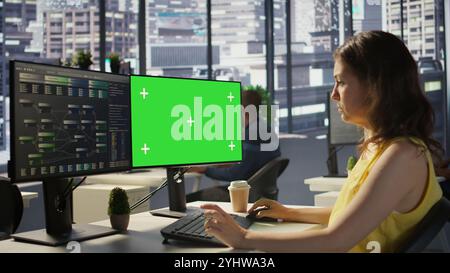 Computer scientist working, doing software debugging using mockup PC, troubleshooting errors. Woman in office fixing coding issues using green screen computer, solving tasks, camera B Stock Photo