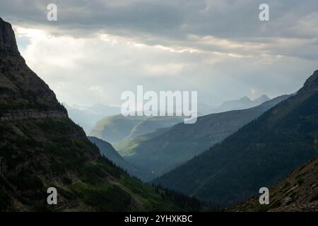 Sun Breaks Through Rain Clouds To Light Distant Mountains Beyond Mount Oberlin in Glacier National Park Stock Photo