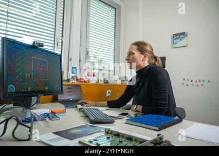 Engineer Sophie Baron analysing a printed circuit board layout featuring radiation-hard custom ASICs (Application-Specific Integrated Circuits) and modules at CERN (European Organization for Nuclear Research). Baron is the leader of the Back-End section in the EP-ESE group in charge of Electronic Systems for Experiments. She also specialises in timing distribution systems for Large Hadron Collider (LHC) experiments, delivering high-precision LHC Bunch Clock signals into the detectors. Stock Photo