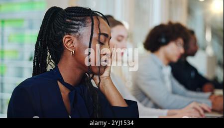 Black woman, employee and tired at office with burnout, exhausted and overworked as technician consultant. Female person, call center agent and Stock Photo