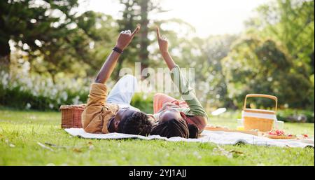 Pointing, picnic and black couple in nature relax on blanket for bonding, relationship and trust outdoors. Dating, park and man and woman look at sky Stock Photo