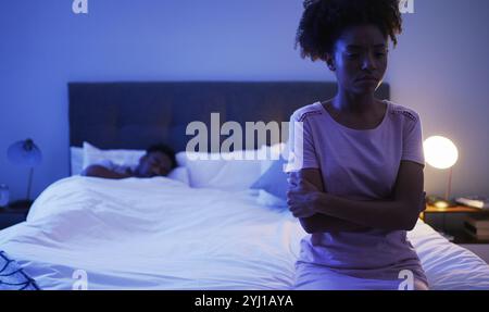 Depressed, woman and bed with African couple, night and marriage trouble from infertility with stress and fight. Bedroom, sit and thinking of divorce Stock Photo