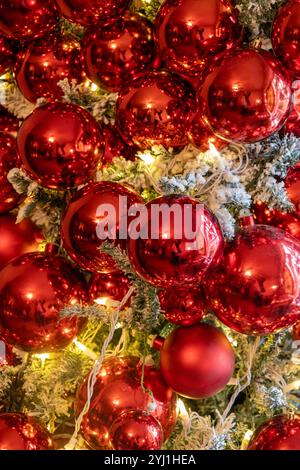 Full frame abstract texture background of shiny red holiday ornaments hanging on a frocked indoor Christmas tree Stock Photo