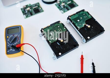 Multimeter, hardware or circuit board with tester for electrical engineering, repair or technician service on desk. Closeup, hard drive and storage Stock Photo