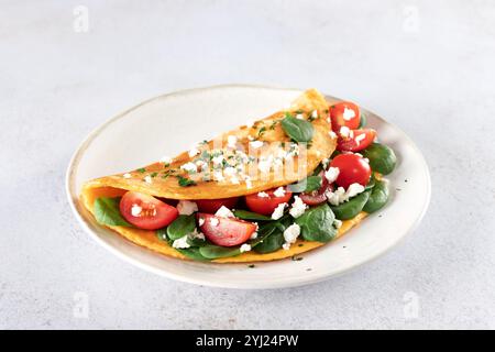 Stuffed omelette with tomatoes, cheese and spinach on a white background.  Stock Photo