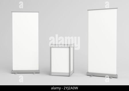 Two blank roll-up banners flank a white promotional counter stand, ideal for branding and display purposes at trade shows, exhibitions, and marketing Stock Photo