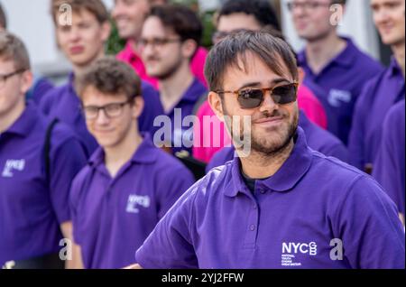 Late summer in Framlingham Suffolk the National Youth Choir of Great Britain in matching purple polo shirts perform an outdoor concert on the Market Stock Photo