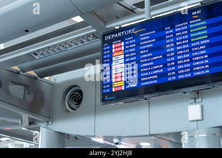 A digital departures board at an airport displaying flight information, including airline, flight number, destination and boarding gate. Stock Photo