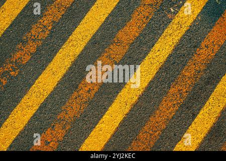 Diagonal yellow caution strip lines painted on black asphalt surface, top view Stock Photo