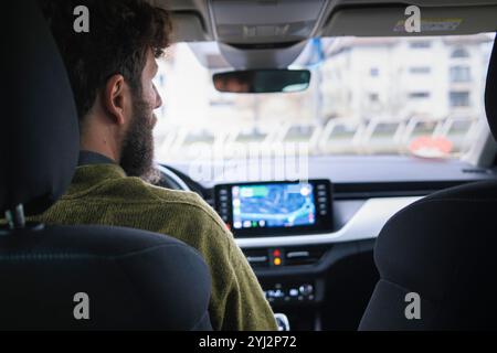 Man driving a car with a focus on the infotainment system and dashboard. Stock Photo