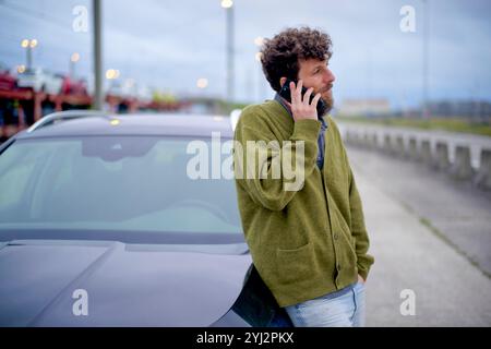 Man talking on a mobile phone while leaning on his car by the roadside, Belgium Stock Photo