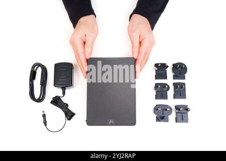Kyiv, Ukraine - October 23, 2024: Person demonstrating Seagate Expansion portable hard drive with power adapter, cables, and various plug types on a w Stock Photo