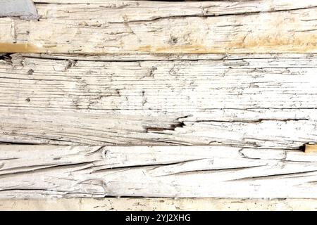 Old cracked wooden surface with a distressed weathered texture. The peeling white paint and deep cracks add a rustic and vintage appeal, perfect for d Stock Photo