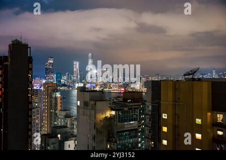 Brightly lit high-rise buildings illuminate the Hong Kong skyline at night, showcasing the vibrant urban atmosphere and colorful city lights along the Stock Photo