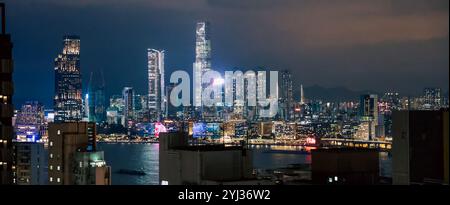 A breathtaking view of Hong Kong's skyline at night, featuring bright lights reflecting off the water and towering buildings against the dark sky. Stock Photo