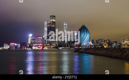 A breathtaking view of Hong Kong at night, featuring illuminated skyscrapers along the waterfront with reflections on the water. Stock Photo