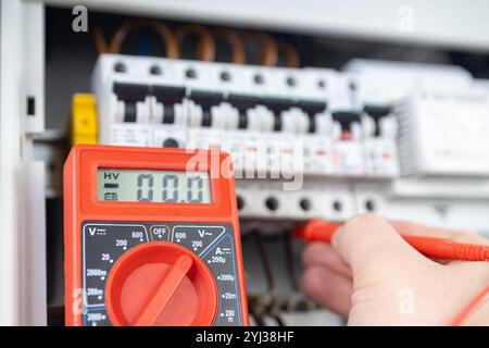 Electrician Measuring Voltage with Multimeter in Circuit Breaker Panel Stock Photo