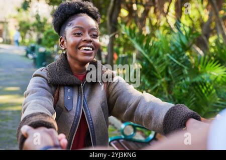 Joyful Woman Holding Hands Outdoors in a Lush Green Park Setting on a Sunny Day Stock Photo