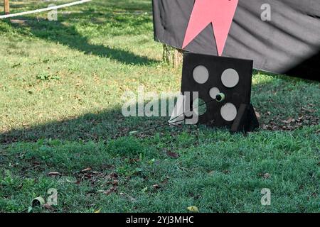 A children's archery target set up in a park, with arrows hitting the bullseye. Perfect for outdoor activities and archery training. Stock Photo