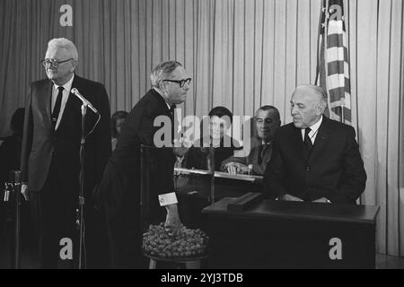 Congressman Alexander Pirnie reaching into a container of draft numbers (center) as others look on, including retiring Selective Service Director Lt. General Lewis Blaine Hershey (left) and Deputy Director Col. Daniel O. Omer (right) at the Selective Service Headquarters during the nationwide draft lottery. USA. 1 December 1969 Stock Photo