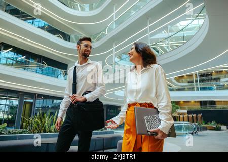 Two corporate professionals engage in a conversation about innovation and career growth in a contemporary office setting emphasizing business relation Stock Photo