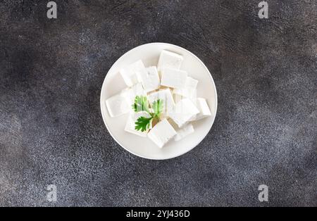 Indian paneer cheese made from fresh milk and lemon juice, cut into cubes on grey background. Top view. Copy space Stock Photo