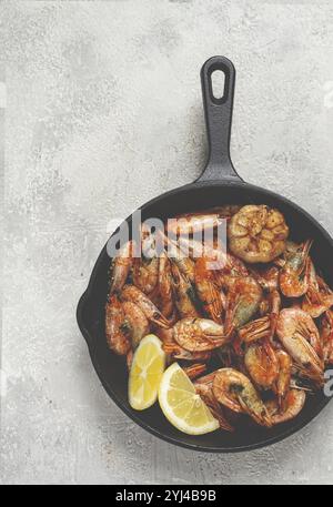 Fried shrimps, in a cast-iron pan, shrimps for beer, in a newspaper, on a gray table, there are no people Stock Photo