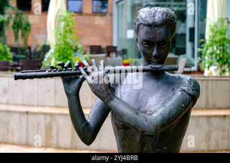 Sculpture of a flutist making music in front of the Joseph Elsner Philharmonic Concert Hall (Filharmonia Opolska) in Opole, Opole Voivodeship, Poland. Stock Photo