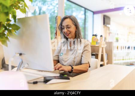Smiling and friendly caucasian female pharmacist working with computer in the counter of the store Stock Photo