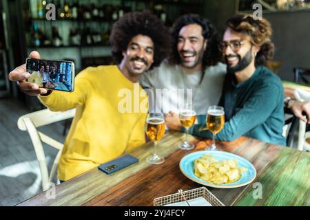 Happy friends taking selfie and drinking beer at the bar Stock Photo