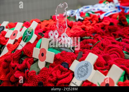 Clear plastic Lest We Forget soldier sign surrounded by knitted poppies and wooden remembrance crosses Stock Photo