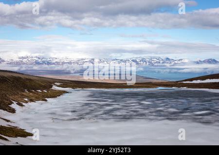 Lake Vatnsskard in Storurd area in East Iceland, frozen glacial lake covered with snow, north coast of Iceland with mountains in the background. Stock Photo