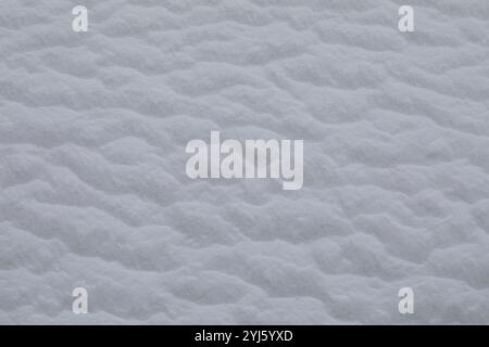 Close-up image of softly rippled snow texture showcasing the natural patterns formed by wind and weather. The snow appears fluffy and serene, evoking Stock Photo