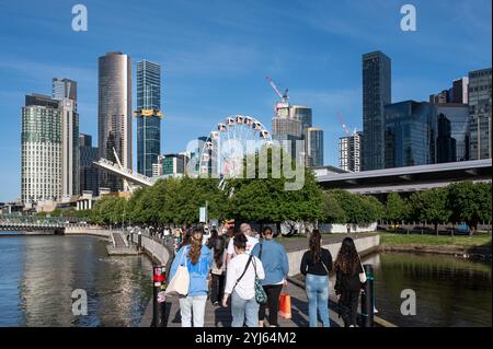 28.10.2024, Melbourne, Victoria, Australia - People walk along South Wharf Promenade by the Yarra River with the skyline of Melbourne CBD in Southbank. Stock Photo