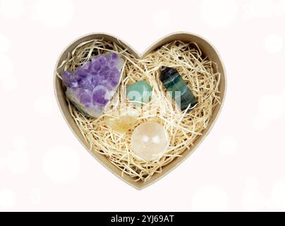 Top view of open heart shaped gift box with shredded wood strips - gift box filler and semi precious stones inside. Spiritual healing gift concept. Stock Photo