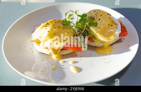 Eggs Royale served with pea shoots. The dish is a variation on Eggs Benedict, with salmon replacing the ham. Stock Photo