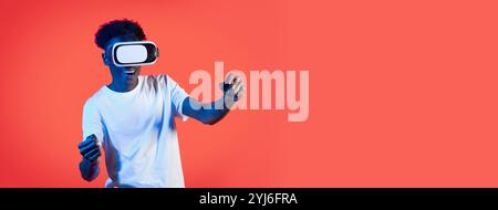 A young man is fully immersed in a virtual reality experience, wearing a headset and smiling while interacting with digital elements. The vibrant back Stock Photo