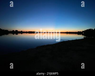 Beautiful summer sunset over a lake at night from the shore, reflections over the water, at Holmes Park in Lincoln, Nebraska, United States Stock Photo